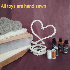 May include: A stack of different colored faux fur fabrics, a white heart-shaped wire, two spools of thread, and three bottles of paint. The text "All materials are only high quality" and "All toys are hand sewn" is visible at the top of the image.
