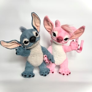 Puede incluir: Dos figuras de peluche de una criatura alien&iacute;gena azul y rosa. La figura azul tiene orejas grandes y una nariz negra. La figura rosa tiene un mech&oacute;n de pelo y una barriga blanca. Ambos tienen ojos grandes y est&aacute;n de pie.