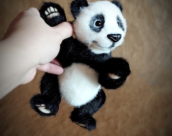 May include: A black and white panda bear plush toy with a smiling face. The panda is wearing a black and white fur coat and has black eyes and a black nose.