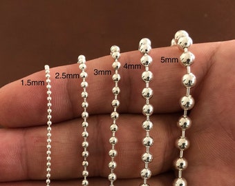 May include: Five silver ball chain necklaces of different sizes, laid out on a hand, with the size of each chain labeled in millimeters: 1.5mm, 2.5mm, 3mm, 4mm, and 5mm.