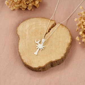 Op de afbeelding: Zilveren ketting met een palmboom hanger. De hanger heeft een halve maan bovenop de boom.