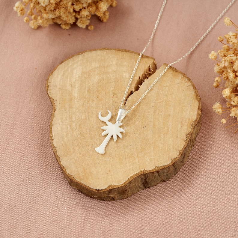 Op de afbeelding: Zilveren ketting met een palmboom hanger. De hanger heeft een halve maan bovenop de boom.