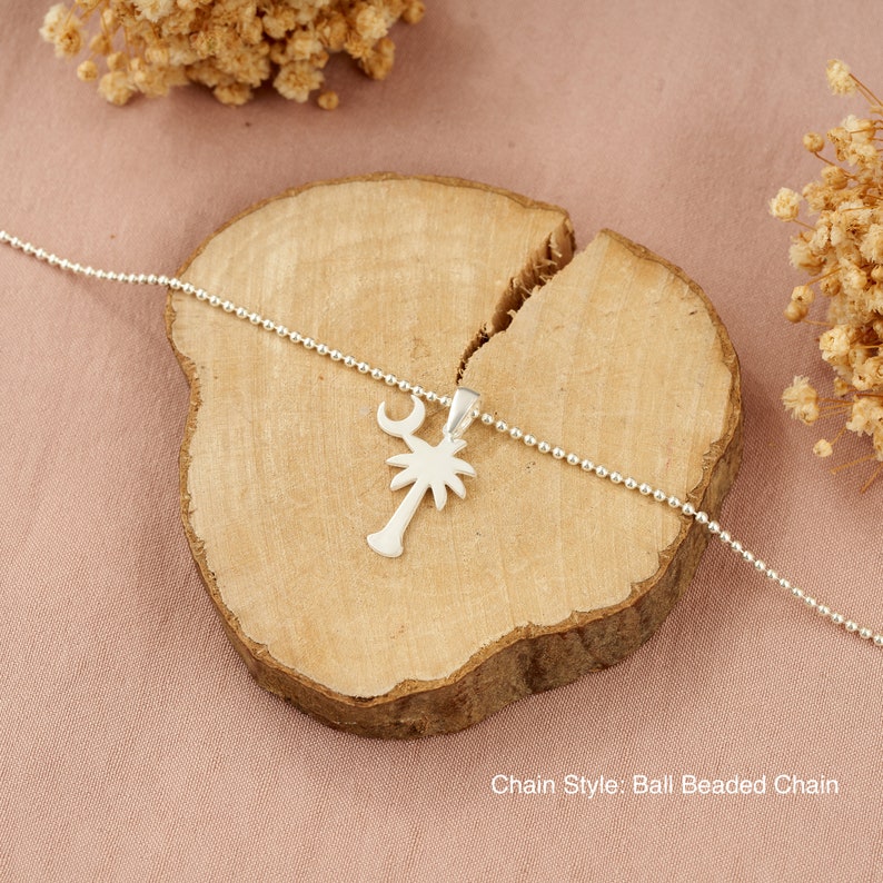 Op de afbeelding: Zilveren ketting met een palmboom hanger en een halve maan bedel. De ketting is een bal kralen ketting. Kettingstijl: Bal kralen ketting