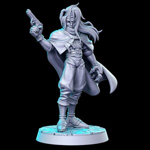 Puede incluir: Una figura impresa en 3D de color gris de un personaje con el pelo largo, que lleva una capa larga y sostiene una pistola. La figura est&aacute; de pie sobre una base circular.