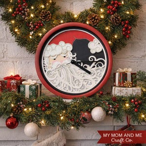 Puede incluir: Un reloj de Navidad redondo con un marco rojo, que presenta un diseño en capas de Papá Noel. La esfera del reloj tiene un diseño en blanco y negro con un fondo rojo. El reloj está rodeado de decoraciones navideñas.