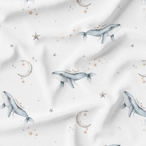 May include: White fabric with a repeating pattern of watercolor whales, crescent moons, and stars in shades of blue, gray, and gold. The whales have small boats on their backs, creating a whimsical, dreamy design.