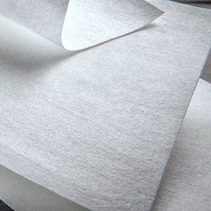 Puede incluir: Primer plano de varias hojas de tela blanca no tejida. La tela tiene una superficie ligeramente texturizada y un aspecto suave y mate. Una hoja está parcialmente despegada, revelando las capas inferiores. El material parece ligero y flexible.