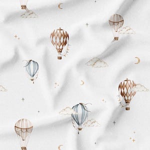 May include: White fabric with a repeating pattern of watercolor hot air balloons in shades of brown, blue, and cream. The design includes clouds, crescent moons, and stars, creating a whimsical, dreamy aesthetic.