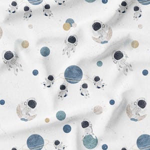 May include: White fabric with a repeating pattern of astronauts, planets, and stars. The astronauts are in space suits, some floating, others on moons or planets. Planets are blue, gold, and teal. A whimsical, space-themed design.