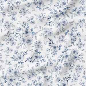 May include: White fabric with a repeating pattern of blue floral bouquets and leaves. The watercolor-style design features various sizes of flowers and foliage, creating a delicate and elegant aesthetic.