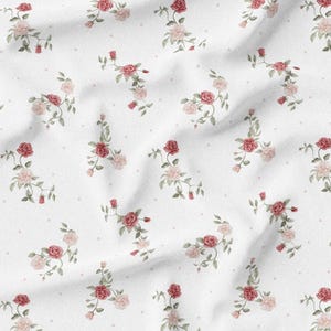 May include: White fabric with a repeating pattern of watercolor roses in shades of red and pink, interspersed with small, light pink dots. The roses are arranged in delicate clusters with green leaves.