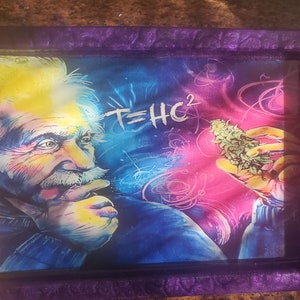 May include: A purple resin tray with a glass insert featuring a colorful illustration of Albert Einstein with the equation "E=HC^2" and a marijuana bud.