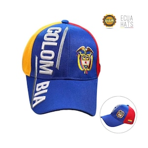 Puede incluir: Gorra de béisbol azul con la palabra "COLOMBIA" en letras blancas. La gorra presenta el escudo de armas colombiano y una combinación de colores amarillo, rojo y azul. El sombrero tiene una visera curva y un pequeño botón redondo en la parte superior.