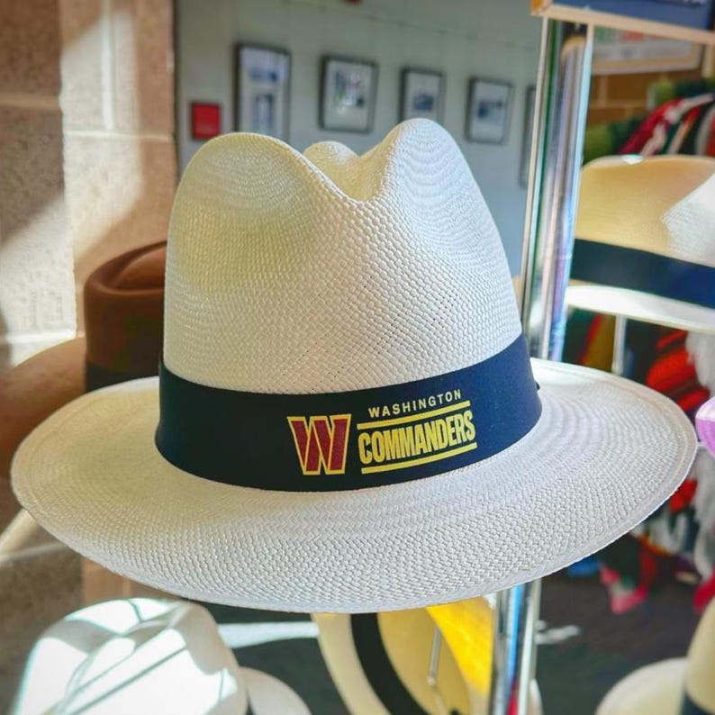 Puede incluir: Sombrero de paja blanco con una banda negra y las palabras "WASHINGTON COMMANDERS" en letras amarillas y rojas.