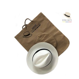 May include: A white Panama hat with a black ribbon, packaged in a brown paper bag with the text "Ecua Hats The Original Panama Made in Ecuador".