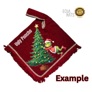 May include: A burgundy poncho with a Christmas tree and Grinch graphic. The poncho has a fringed edge and the words "Ugly Poncho" are printed on the front. The poncho also has the text "Example" printed on the bottom.