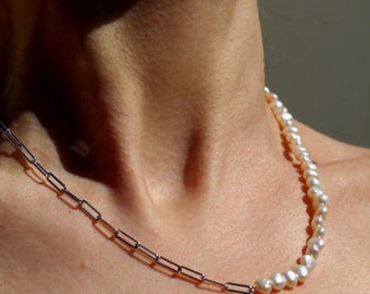 May include: A silver chain necklace with a strand of white pearls attached to one end.