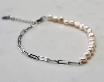 May include: A silver chain bracelet with a row of white pearls. The pearls are uneven in size and shape, giving the bracelet a unique and delicate look.
