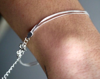 May include: A silver chain bracelet with multiple strands. The bracelet is on a person's wrist.