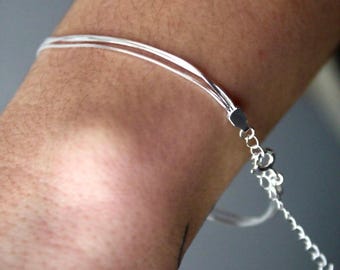 May include: A silver chain bracelet with multiple strands. The bracelet is on a person's wrist.