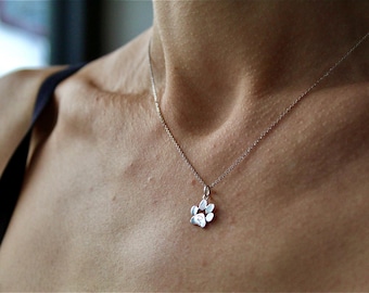 May include: A silver chain necklace with a small paw print pendant.