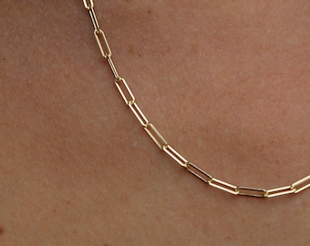 May include: A gold chain necklace with a simple, linked design. The chain is made of small, rectangular links.