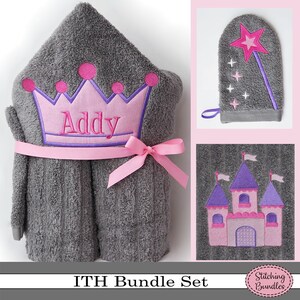 May include: A gray hooded towel with a pink crown and the name "Addy" embroidered on it. The towel is tied with a pink ribbon. The image also shows a gray hand towel with a pink castle and a gray hand towel with a pink wand and star.