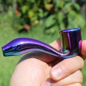 May include: A iridescent purple glass pipe with a curved bowl and a straight stem.