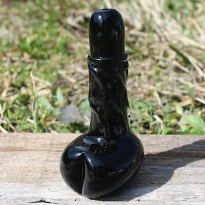 May include: A black glass pipe with a twisted design. The pipe has a bowl at the bottom and a mouthpiece at the top.