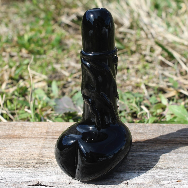 May include: A black glass pipe with a twisted design. The pipe has a bowl at the bottom and a mouthpiece at the top.