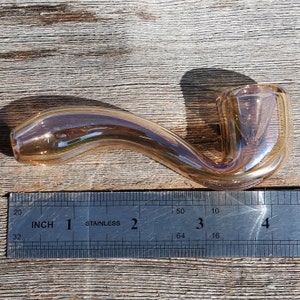 May include: A brown glass pipe with a curved stem and a bowl on the end. The pipe is about 3 inches long and is measured against a ruler.