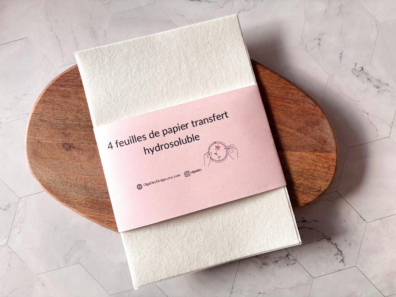 May include: A pack of 4 water-soluble transfer paper sheets. The pack is pink and has the text "4 feuilles de papier transfert hydrosoluble" on the front. The text is in French.