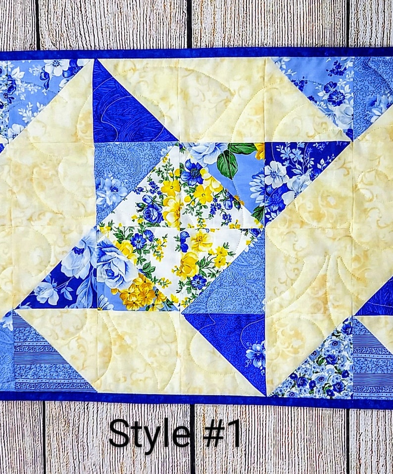 Puede incluir: Un camino de mesa acolchado con un patr&oacute;n floral azul y amarillo. El camino de mesa est&aacute; hecho de cuadrados y tri&aacute;ngulos, y el acolchado se realiza en un patr&oacute;n de espiral. El texto "Style #1" es visible en la parte inferior de la imagen.