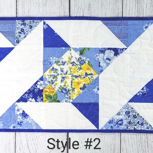 Puede incluir: Un camino de mesa acolchado azul y blanco con un patr&oacute;n floral y un dise&ntilde;o geom&eacute;trico. El camino de mesa tiene un borde azul y el texto "Style #2" est&aacute; impreso debajo del camino de mesa.