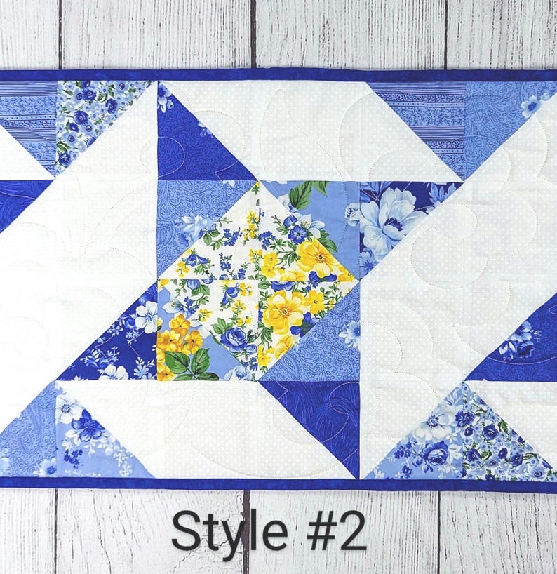 Puede incluir: Un camino de mesa acolchado azul y blanco con un patr&oacute;n floral y un dise&ntilde;o geom&eacute;trico. El camino de mesa tiene un borde azul y el texto "Style #2" est&aacute; impreso debajo del camino de mesa.