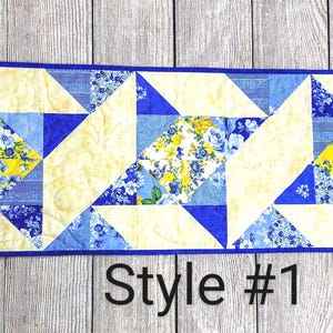 Puede incluir: Un camino de mesa acolchado azul y amarillo con un patr&oacute;n geom&eacute;trico. El camino de mesa est&aacute; hecho de tela con estampado floral. El texto "Style #1" es visible en la parte inferior de la imagen.