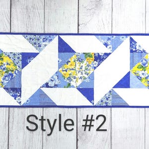 Puede incluir: Un camino de mesa azul y amarillo con un patr&oacute;n geom&eacute;trico. El camino de mesa est&aacute; hecho de tela y tiene un fondo blanco con tri&aacute;ngulos de estampado floral azul y amarillo. El texto "Style #2" est&aacute; impreso debajo del camino de mesa.
