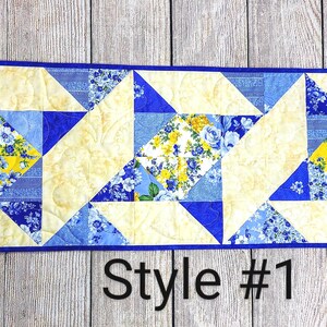 Puede incluir: Un camino de mesa acolchado azul y amarillo con un patr&oacute;n geom&eacute;trico. El camino de mesa est&aacute; hecho de recortes de tela y tiene un borde azul. El texto "Style #1" est&aacute; impreso debajo del camino de mesa.