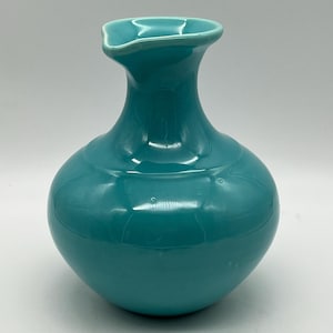 以下が含まれることがあります： 丸みを帯びたボディと広がった首を持つターコイズブルーのセラミック花瓶