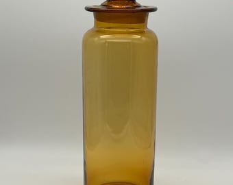Peut inclure: Une grande bouteille en verre ambré avec un bouchon en verre. La bouteille a une forme cylindrique et une surface lisse et transparente.