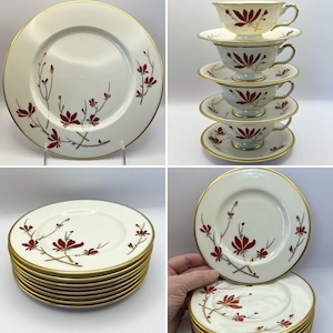 May include: A set of 10 white porcelain teacups and saucers with a delicate floral design in shades of red and gold. The cups and saucers have a gold rim.