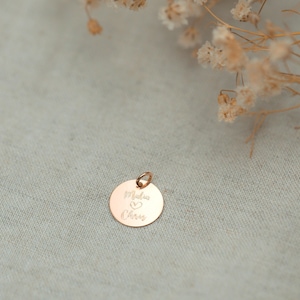 May include: A gold-toned round charm with the inscription "Maddie & Chris" and a heart symbol.