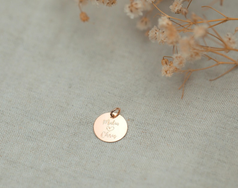 May include: A gold-toned round charm with the inscription "Maddie & Chris" and a heart symbol.