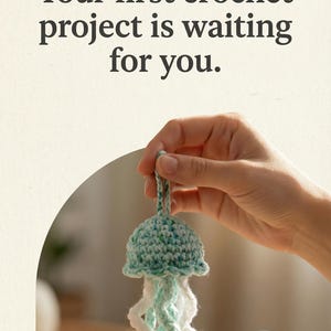 May include: A teal and white crocheted jellyfish is displayed. The jellyfish has a rounded top and curly tentacles. The image also includes the text "create" and "Your first crochet project is waiting for you."