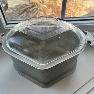 May include: A silver aluminum casserole dish with a glass lid. The lid has a raised design of a knight's helmet and two crossed swords.