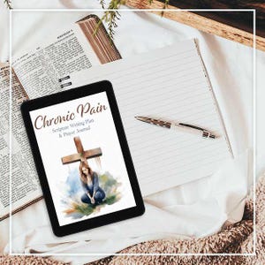 May include: A black tablet displaying a journal cover with the title "Chronic Pain" and the subtitle "Scripture Writing Plan & Prayer Journal." An open Bible, lined notepad, and pen are also visible on a white surface.
