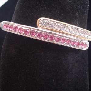 May include: A silver and gold bangle bracelet with pink and clear rhinestones.