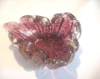 Puede incluir: Un plato de vidrio en forma de corazón con un patrón de espiral rosa y blanco. El plato está hecho de vidrio transparente con un patrón de espiral rosa y blanco. Es una pieza decorativa que se puede utilizar para joyas u otros objetos pequeños.