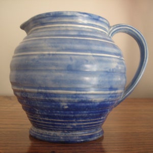 May include: A blue and white ceramic jug with a ribbed design. The jug has a wide mouth and a handle.