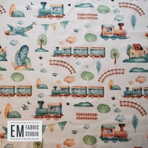 May include: A white fabric with a repeating pattern of watercolor illustrations of trains, clouds, trees, and birds. The trains are green and orange with black wheels. The clouds are white with orange and blue accents. The trees are green with brown trunks. The birds are blue with black beaks. The fabric has the text "EM FABRIC STUDIO" in the bottom left corner.
